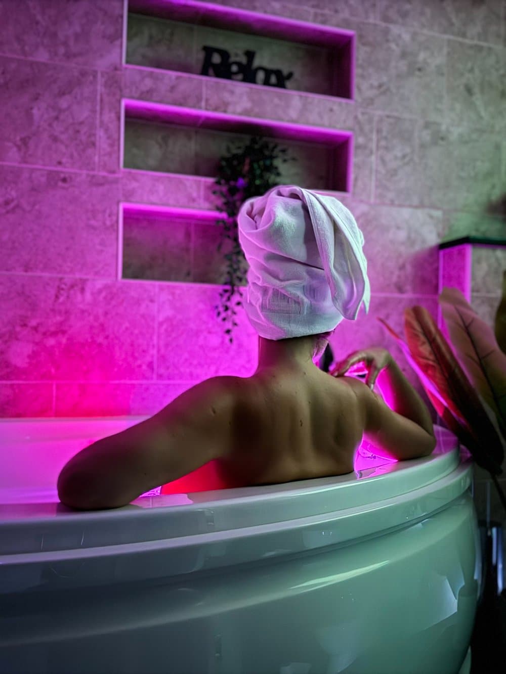 Relaxing in a corner spa bath under soft pink light
